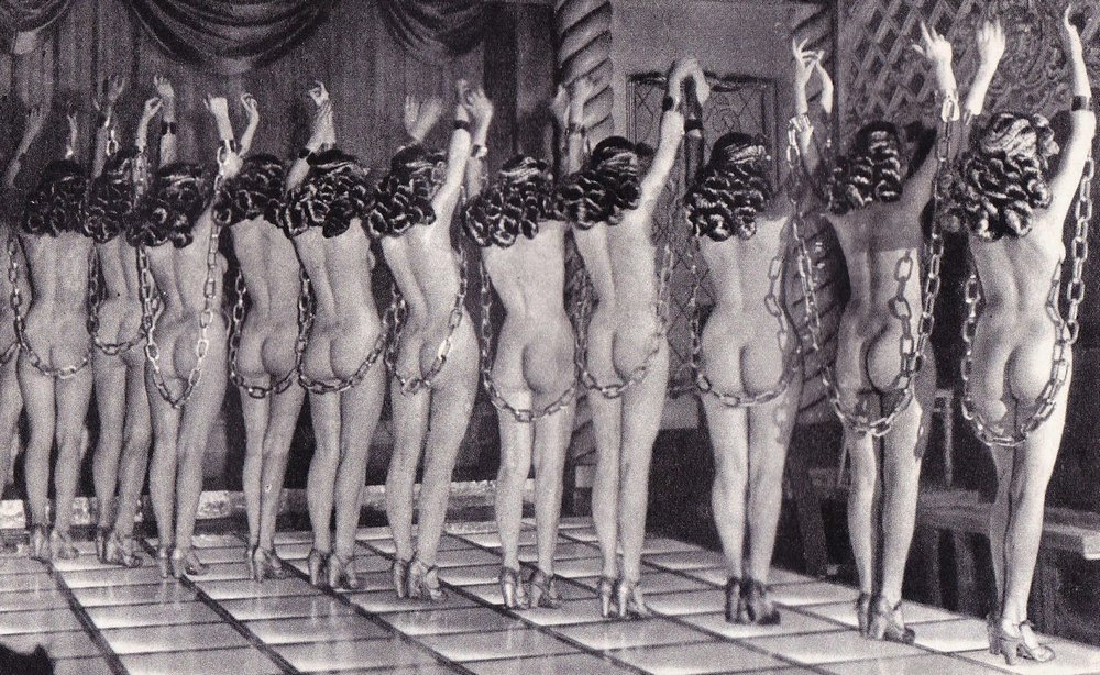 a dozen naked burlesque dancers in chains