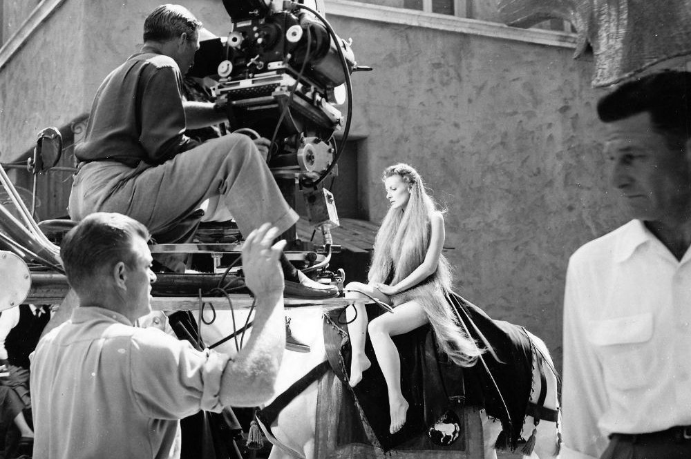 Maureen O'Hara with long hair wears a nude look bodysuit as film crews shoot a scene from the movie Lady Godiva of Coventry 