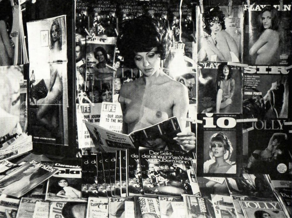 nude woman reading a porno mag at a porn newstand